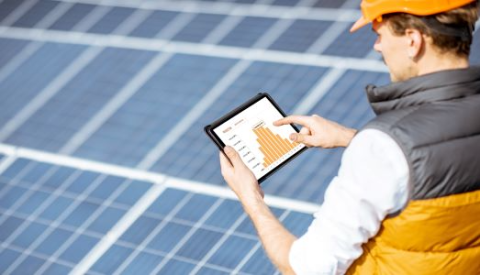 solar panels and man in hard hat with iPad