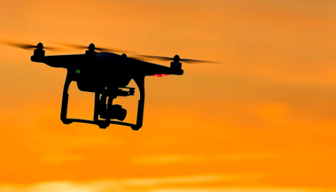 a drone flying against an orange sky