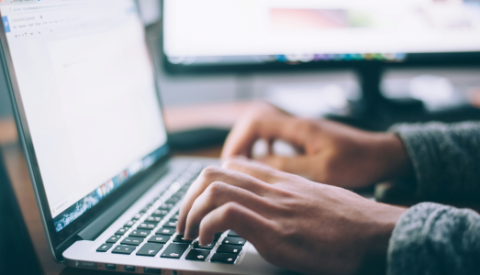 two hands typing on a laptop keyboard